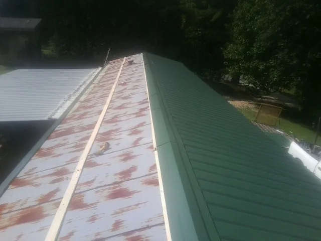 Old rusted panels beside newly installed green metal roofing — Wind Damage Roof Repair by Roofing Brothers in Dodge City