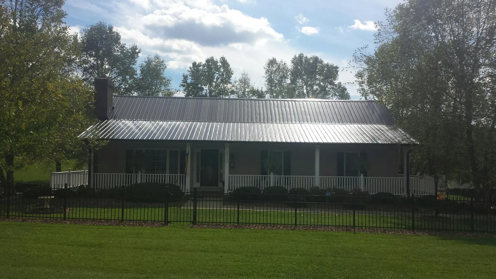 Gray metal roof on a brick ranch with a full width front porch — Gutter Guard Installation work by our crew in Dodge City