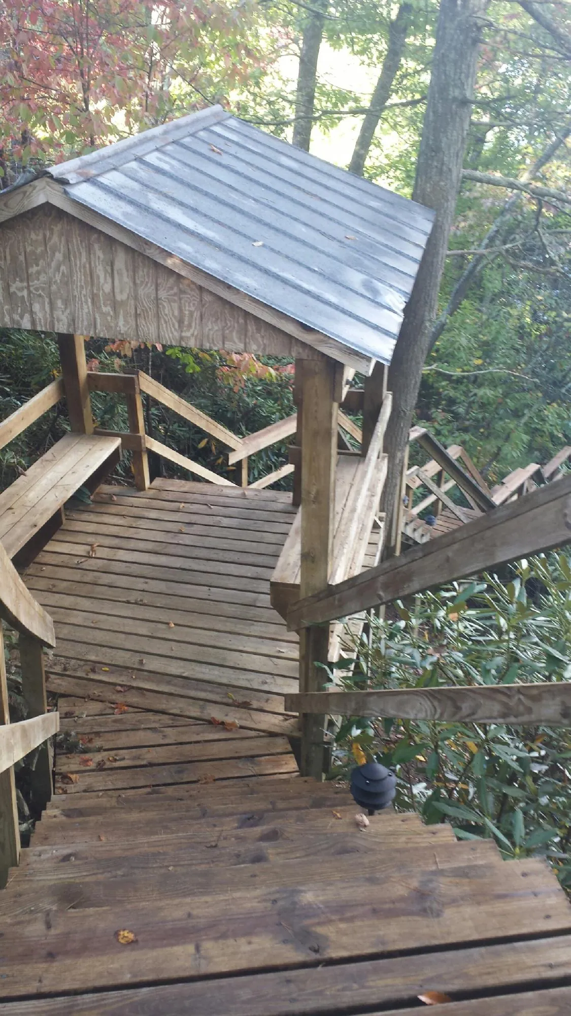 Metal roofed shelter over wooden steps on a wooded walkway — Skylight Repair & Installation work by our crew in Dodge City