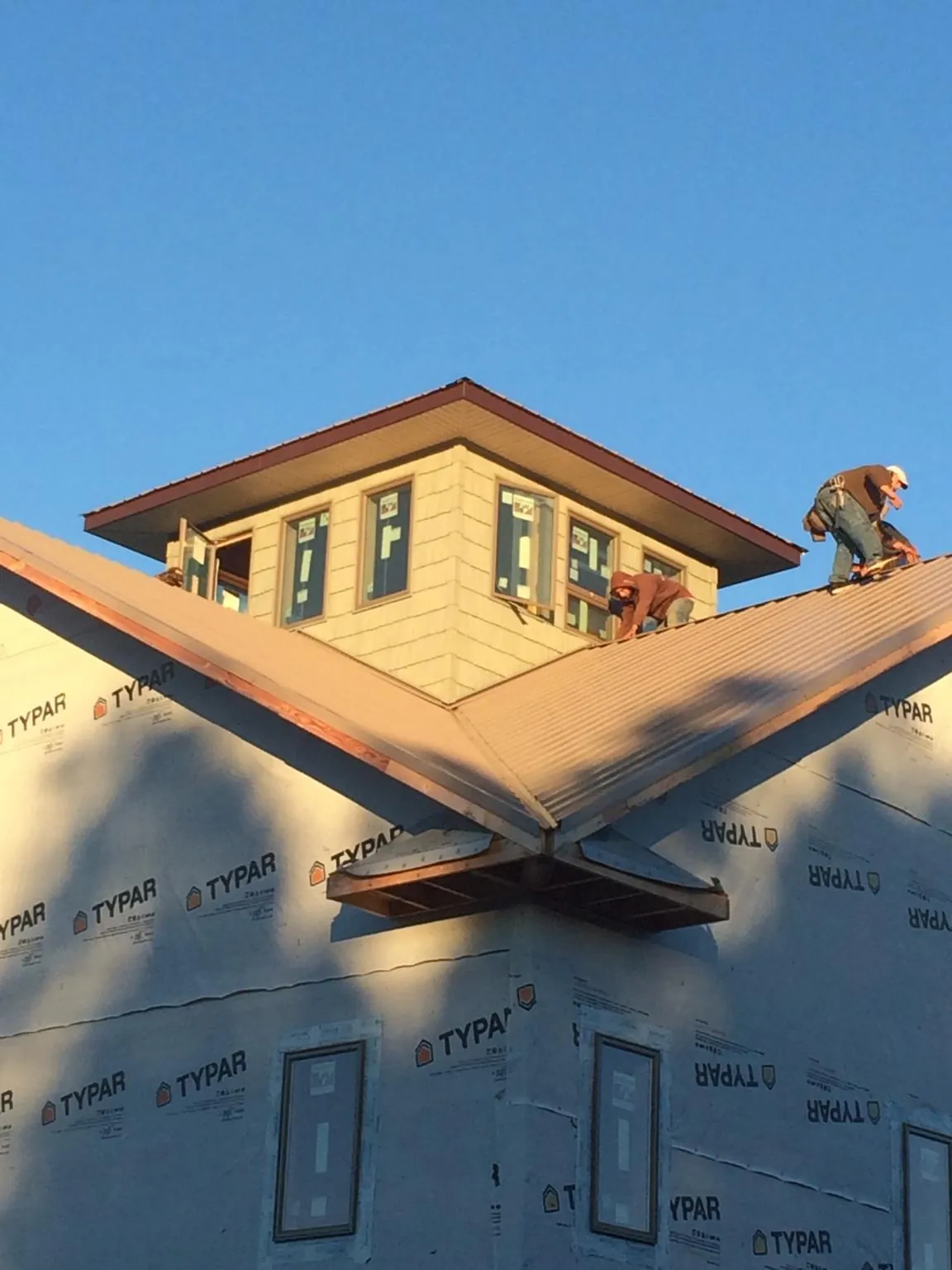 Roofers working around a rooftop cupola on a new metal roof at sunset — Roof Waterproofing in Dodge City by Roofing Brothers